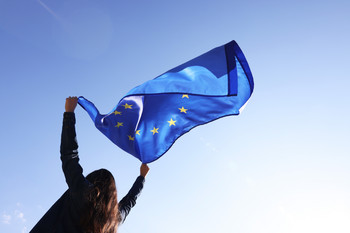 Das Bild zeigt eine Frau mit EU-Fahne.