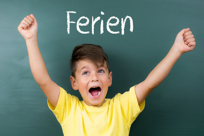 Ein Kind steht vor einer Tafel mit der Aufschrift Ferien Ein Kind steht vor einer Tafel mit der Aufschrift Ferien.