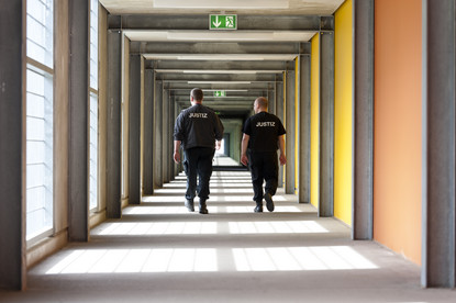 2 Justizbeamte gehen einen Gang entlang.
