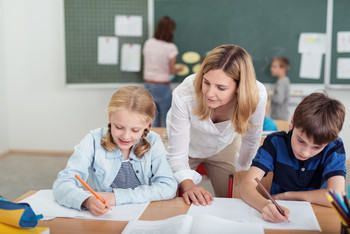 Das Bild zeigt 2 Schüler und eine Lehrerin.