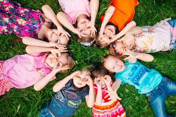 Das Bild zeigt Kinder, die im Gras liegen.
